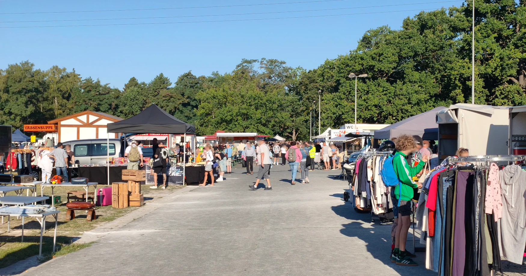 Volle Marktgasse mit Kleiderständern an einem Sonntagvormittag