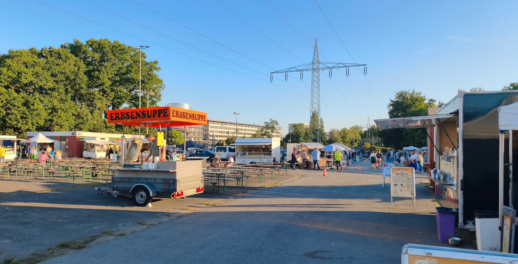 Blick über das Messegelände mit Imbisswagen, Bierbänken und Toilettengebäude
